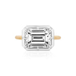 An East-West Collet Setting Emerald Cut Diamond Engagement Ring, showcasing a large rectangular diamond in a white metal prong setting, photographed from above on a white background.