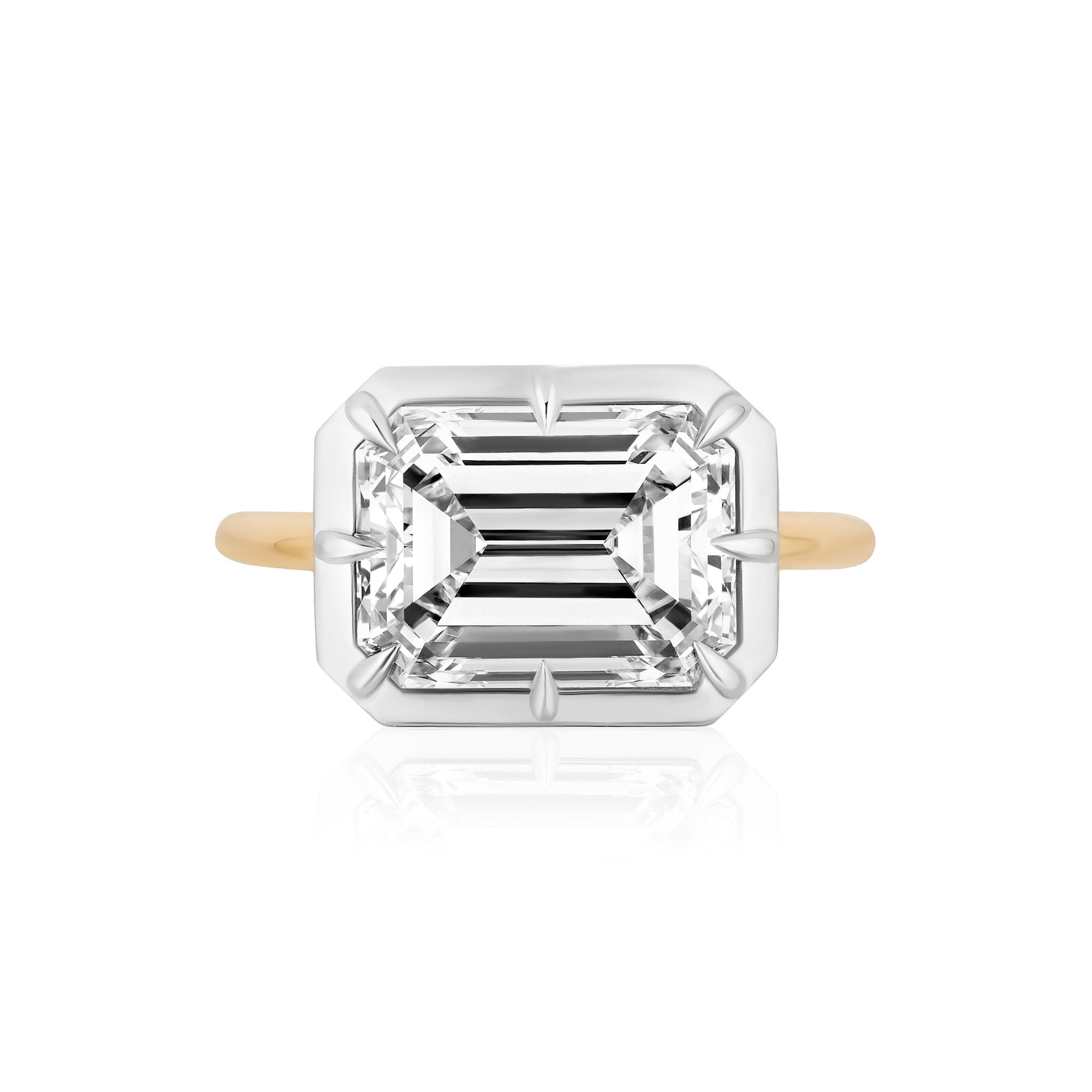 An East-West Collet Setting Emerald Cut Diamond Engagement Ring, showcasing a large rectangular diamond in a white metal prong setting, photographed from above on a white background.