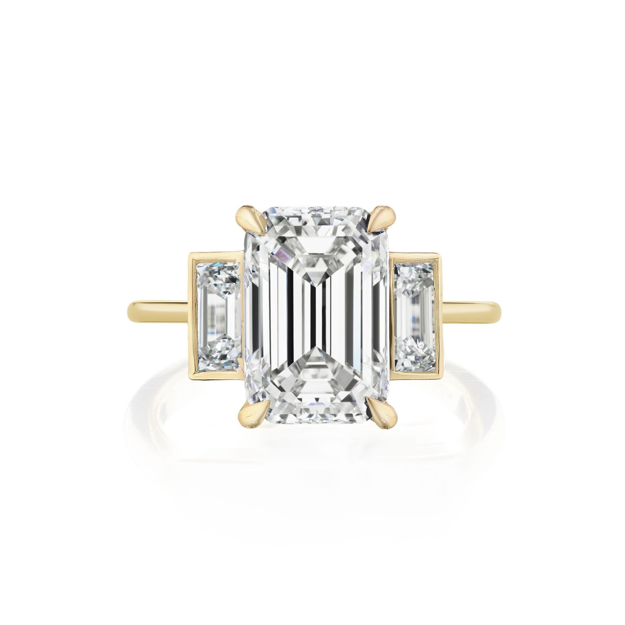 Introducing the Emerald Cut Diamond Engagement Ring with Bezel Set Baguette Side Stones: Featuring a breathtaking emerald cut diamond at its center, this ring is adorned with bezel set baguette diamonds on each side. Expertly crafted in 18k yellow gold, the simple and elegant band enhances the timeless allure of its exquisite design.