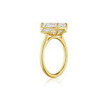 The Emerald Cut Diamond Engagement Ring with Trapezoid Side Stones is crafted in 18k yellow gold and features a large, emerald-cut diamond set in a classic four-prong setting, displayed from the side on a white background.