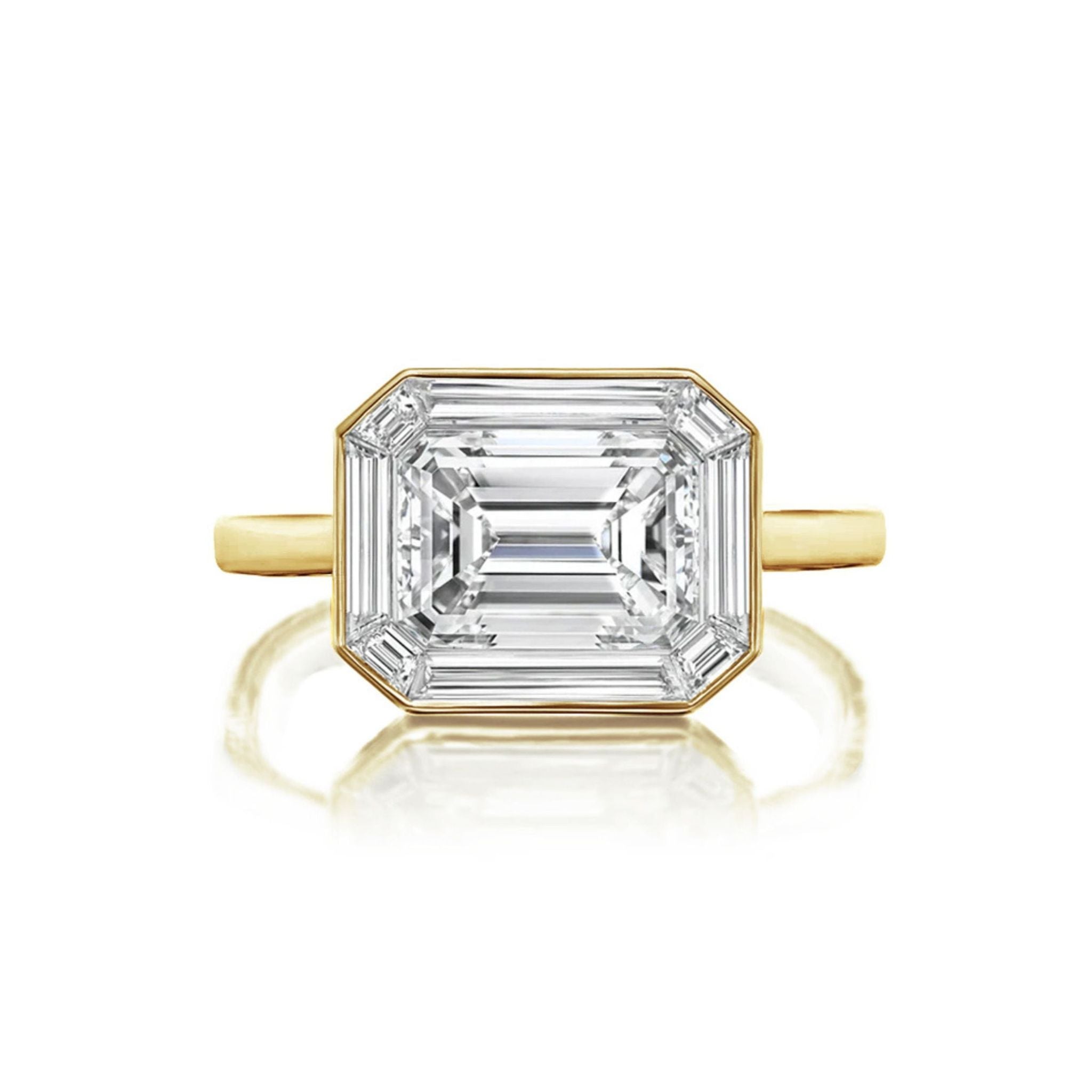 An East-West Set Mosaic Diamond Engagement Ring featuring an emerald-cut diamond surrounded by a baguette halo, elegantly displayed on a simple band and photographed against a white background.