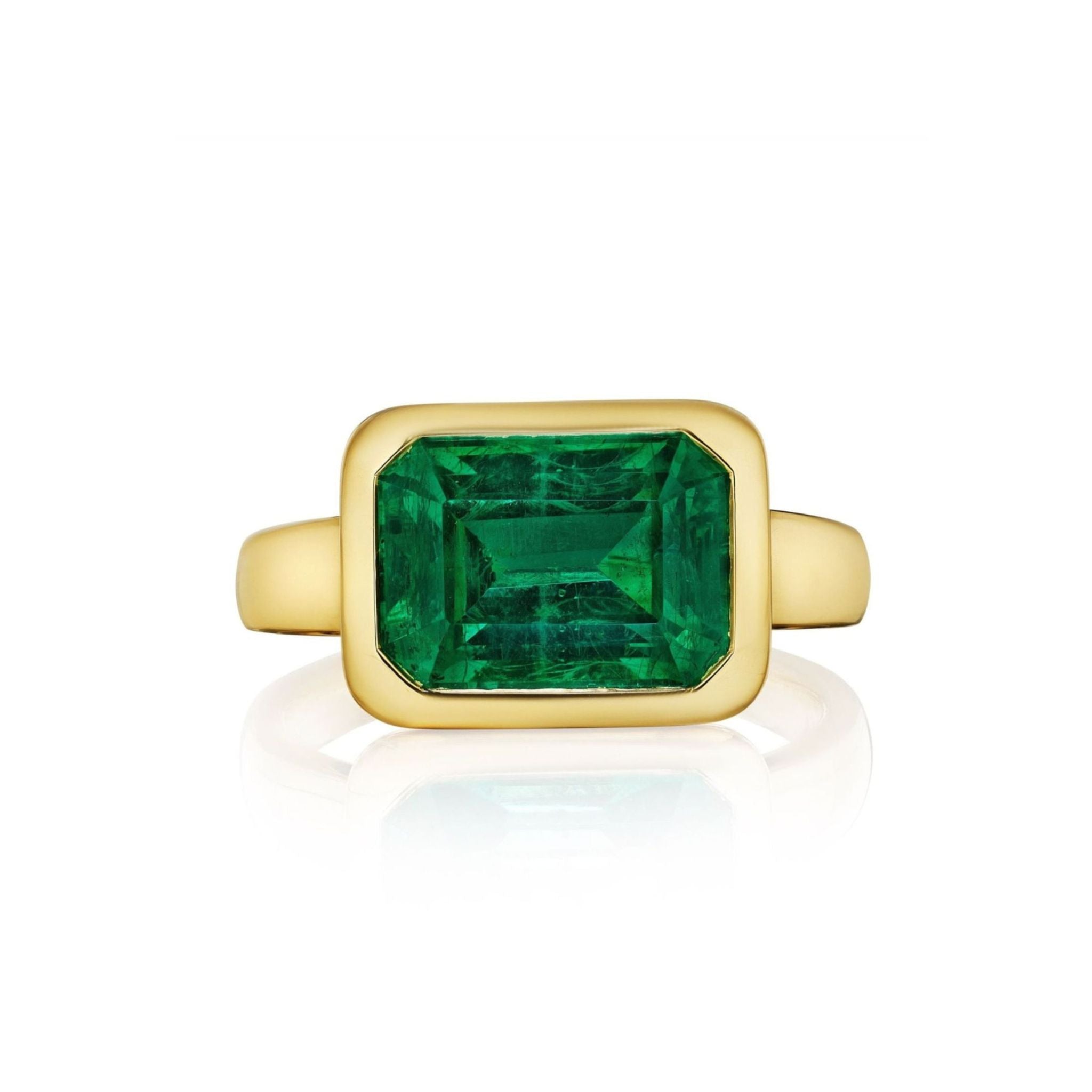 Introducing the East-West Bezel Set Emerald Cut Emerald Engagement Ring in Yellow Gold, featuring a vibrant emerald-cut emerald set horizontally at the center. The luxurious 18k yellow gold band gracefully enhances the gemstone's radiant green hue, creating a timeless and sophisticated look against a white background.