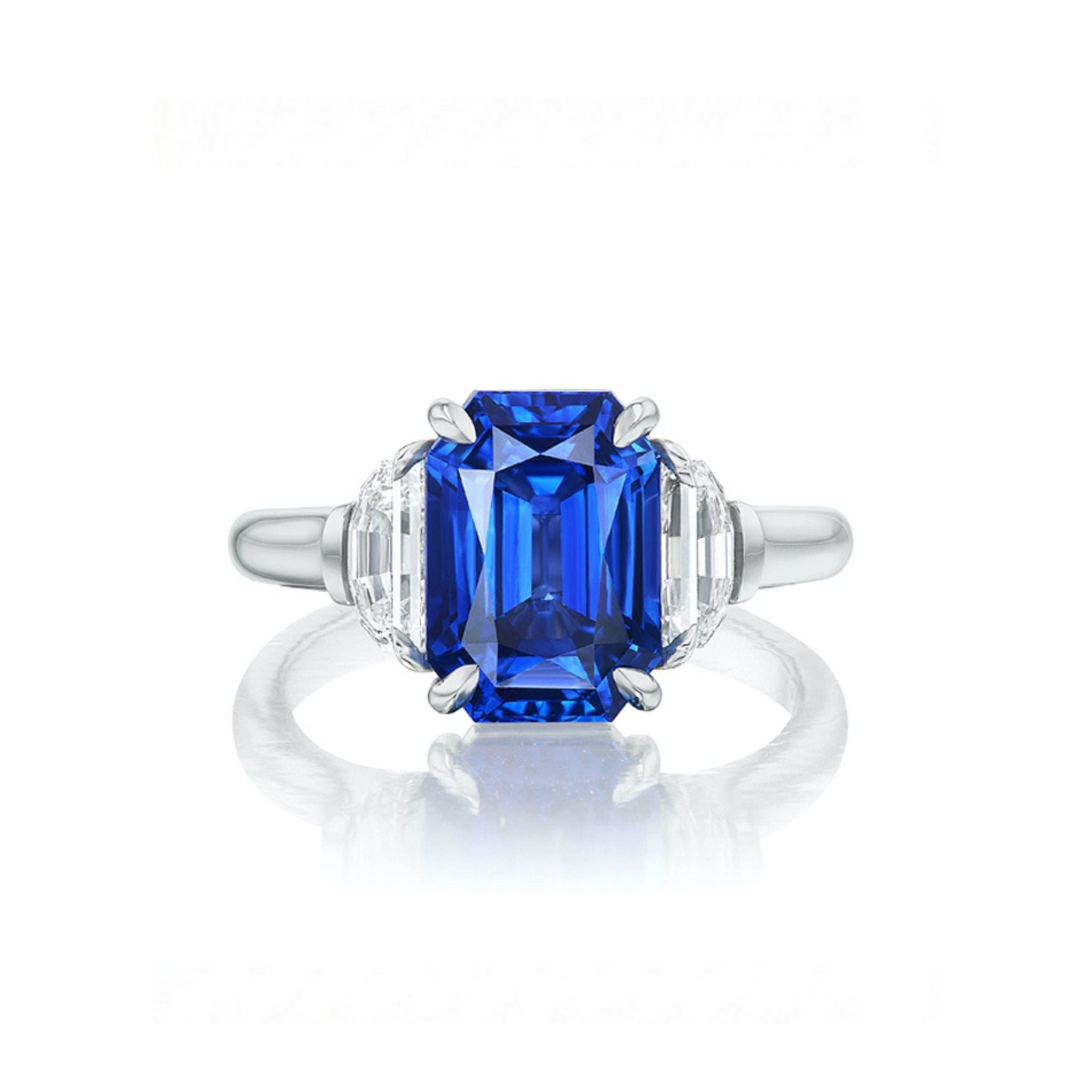 The Emerald Cut Sapphire Engagement Ring with Half Moon Diamond Side Stones showcases a stunning emerald-cut blue sapphire at its center, flanked on each side by sparkling half moon diamond accents, all set against a plain white background.