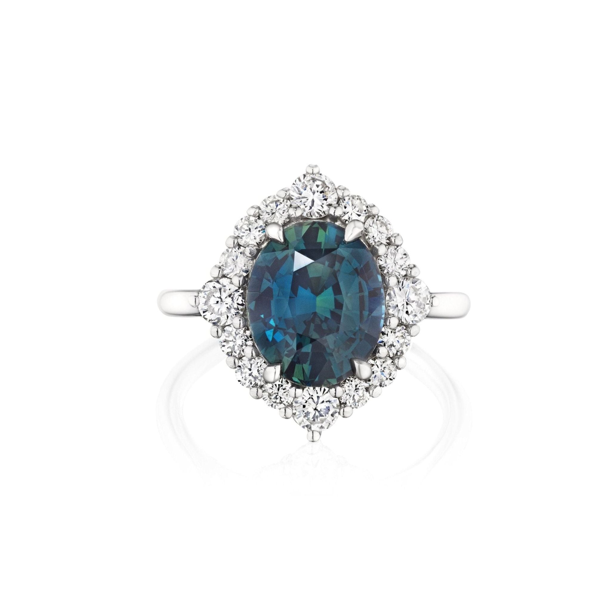 Teal Oval Sapphire Engagement Ring with Diamond Halo displayed on a white background, featuring a vibrant teal oval sapphire at the center and surrounded by a dazzling halo of round white diamonds set in silver.