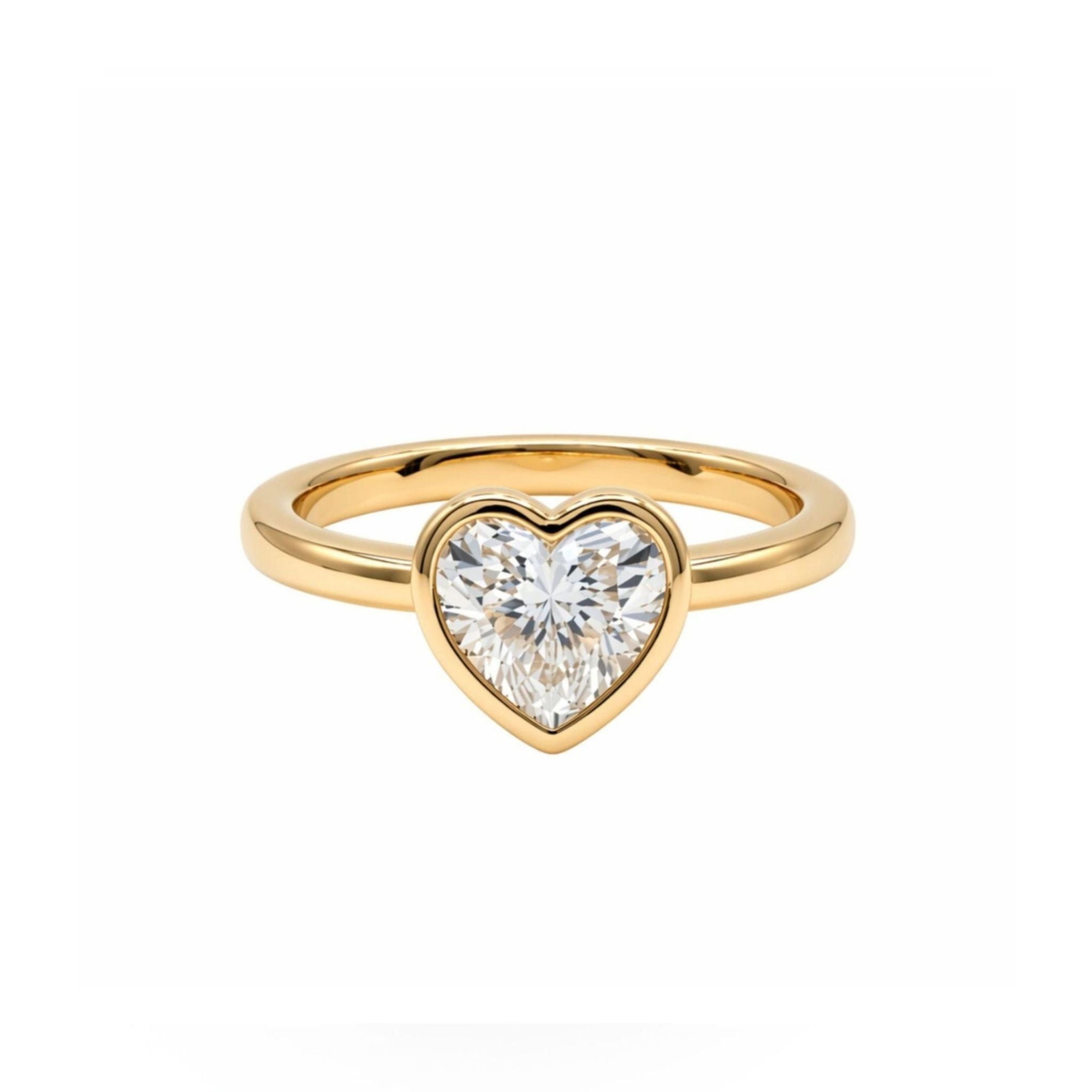 A Bezel Set Heart Shape Diamond Engagement Ring in Yellow Gold is displayed on a plain white background, featuring a central heart-shaped clear diamond.