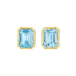 A pair of Bezel Set Emerald Cut Aquamarine Stud Earrings in Yellow Gold are displayed side by side against a white background.