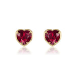 The Ruby Heart Studs in Yellow Gold feature heart-shaped rubies elegantly bezel set in luxurious 18k yellow gold, with delicate reflections beneath them, displayed against a pristine white background.