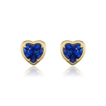 Introducing the Blue Sapphire Heart Studs in Yellow Gold: exquisite 18k yellow gold heart-shaped earrings, each featuring a vibrant blue sapphire at the center, elegantly displayed on a white background with soft reflections for a striking presentation of sapphire jewelry.