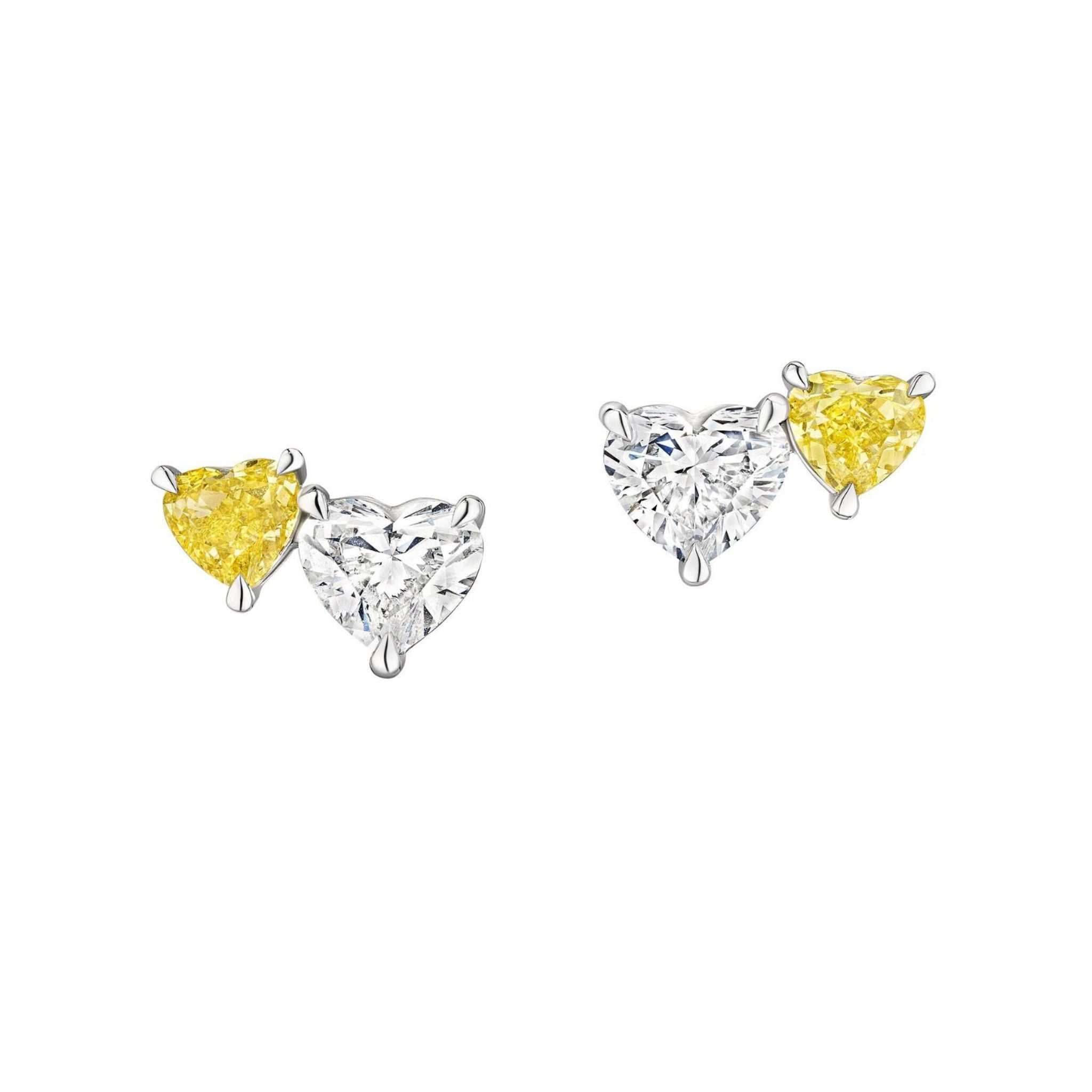The Heart Shaped White and Yellow Diamond Duo Studs feature two pairs of stud earrings, each pair showcasing one heart-shaped white diamond and one heart-shaped yellow diamond, set securely in 18k white gold prongs and elegantly displayed on a white background.