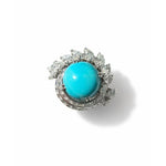 The Turquoise and Diamond Ring showcases a large round turquoise cabochon at its center, encircled by a halo of marquise-cut white gemstones, capturing the timeless elegance of vintage 1970s jewelry, beautifully displayed on a white background.