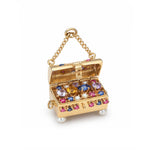 The Vintage Gold and Gem-Set Charm is crafted in 14K gold in the shape of a treasure chest, featuring colorful gemstones, pearls, and a chain handle. The charm’s open lid reveals sparkling rubies and sapphires nestled among other jewels inside.