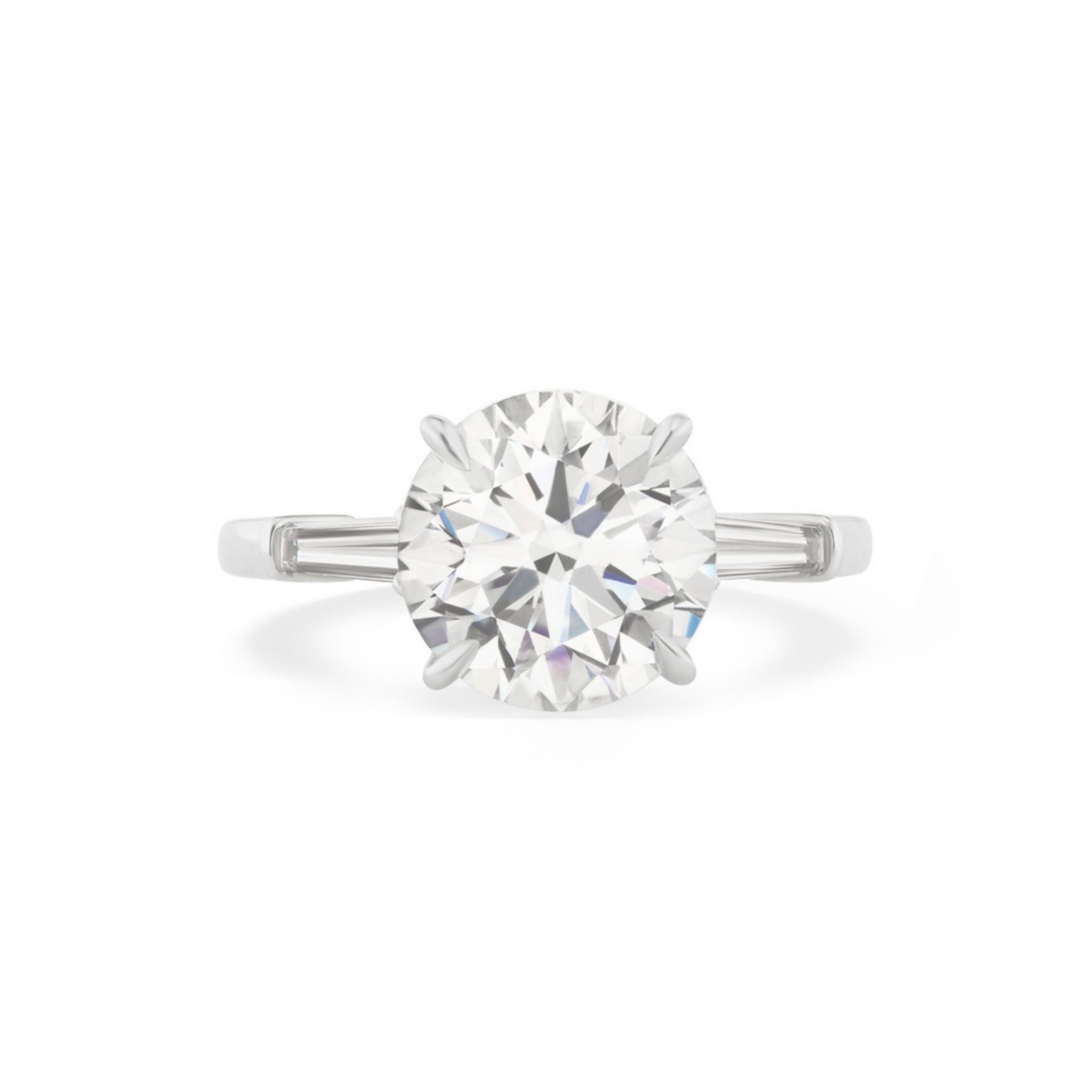 The Round Brilliant Diamond Engagement Ring with Tapered Baguette Side Stones features a stunning round-cut diamond at its center, accented by elegant tapered baguette diamonds on either side—an exquisite celebration ring ideal for commemorating life's most treasured milestones.