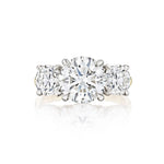 A close-up of the Diamond Engagement Ring with Round Side Stones in Platinum and Yellow Gold, showcasing a dazzling round center diamond accented by two smaller round diamonds, all set elegantly in a polished blend of platinum and yellow gold.