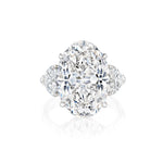 An elegant Oval Diamond Engagement Ring featuring heart-shaped side stones, set in a sleek platinum band and displayed on a white background.