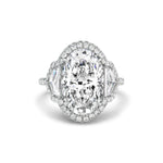 The Cobblestone Pavé Basket Ring features an oval-shaped diamond center stone, accented by a sparkling halo of small round diamonds and two epaulette diamond side stones, elegantly set in your choice of silver or white gold—a timeless bridal ring for your special day.
