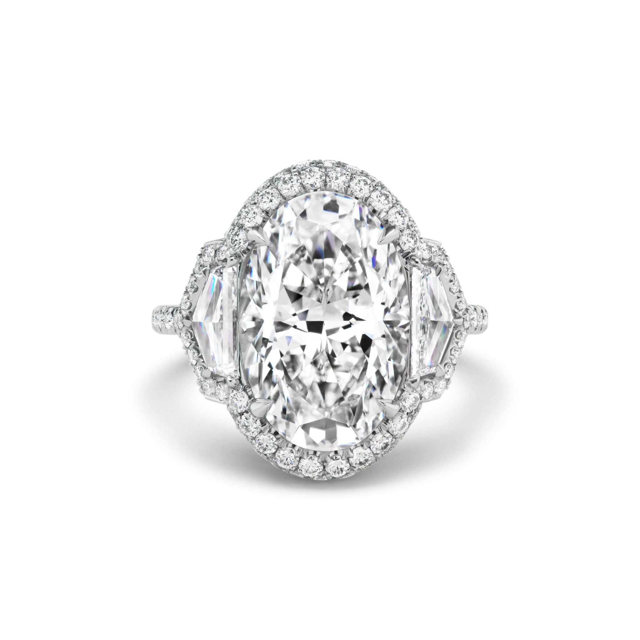 The Cobblestone Pavé Basket Ring features an oval-shaped diamond center stone, accented by a sparkling halo of small round diamonds and two epaulette diamond side stones, elegantly set in your choice of silver or white gold—a timeless bridal ring for your special day.