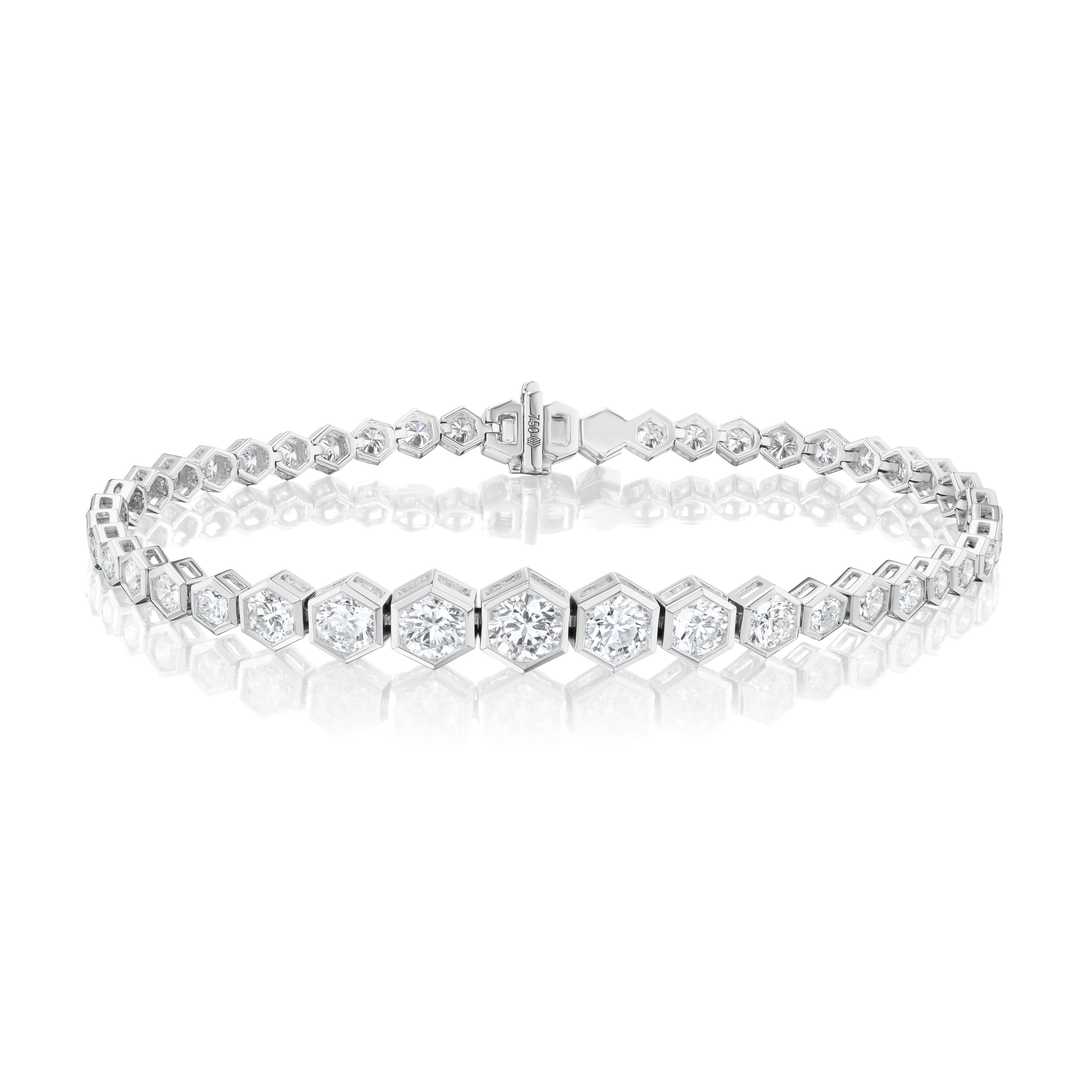 The Graduated Hexagon Bezel Set Diamond Tennis Bracelet in white gold features hexagonal links with round diamonds, shown on a white background with a subtle reflection beneath.