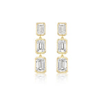The Bezel Set Emerald Cut Diamond Drop Earrings in Yellow Gold feature three vertically aligned emerald cut diamonds in bezel settings, crafted from 18k yellow gold and displayed on a white background.