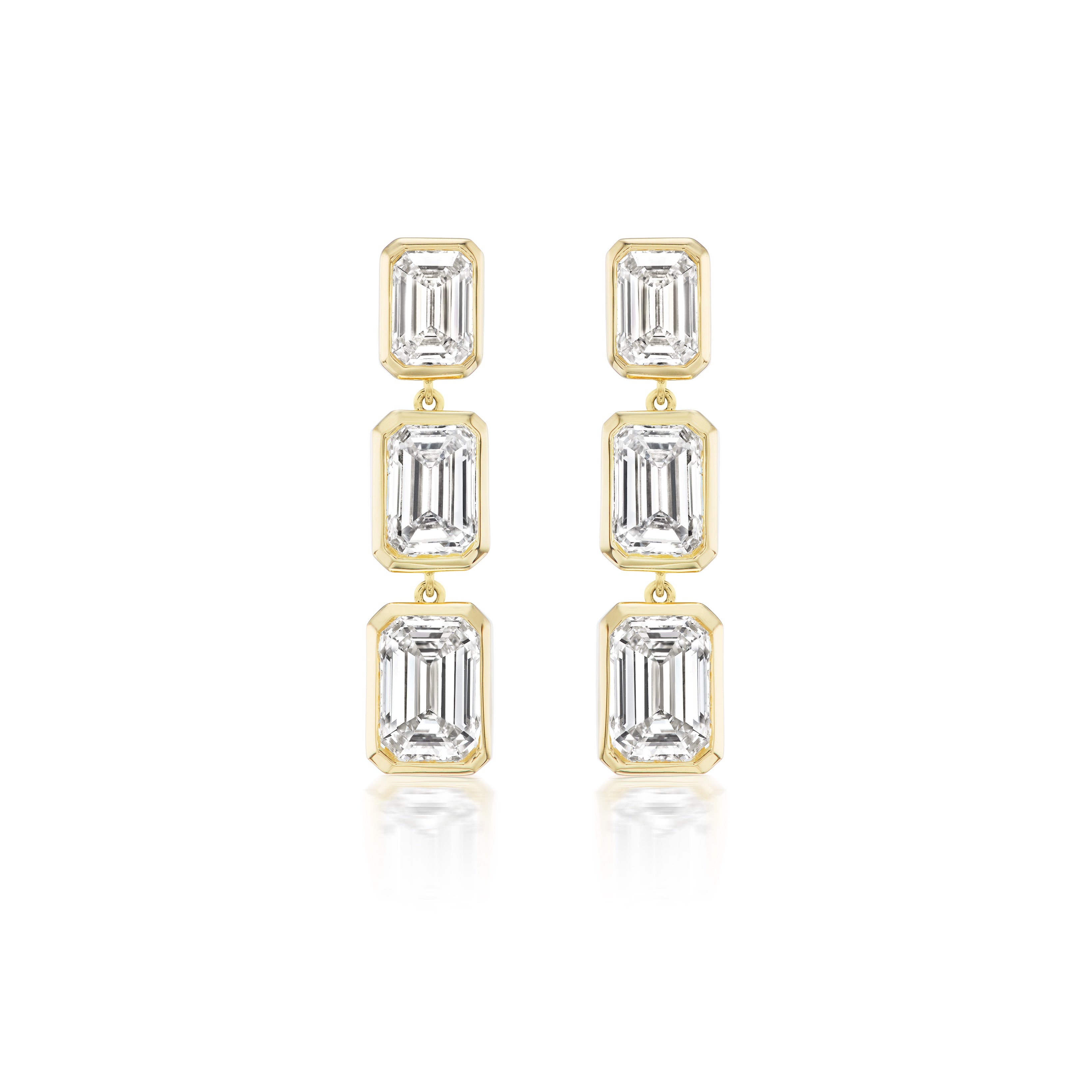 The Bezel Set Emerald Cut Diamond Drop Earrings in Yellow Gold feature three vertically aligned emerald cut diamonds in bezel settings, crafted from 18k yellow gold and displayed on a white background.