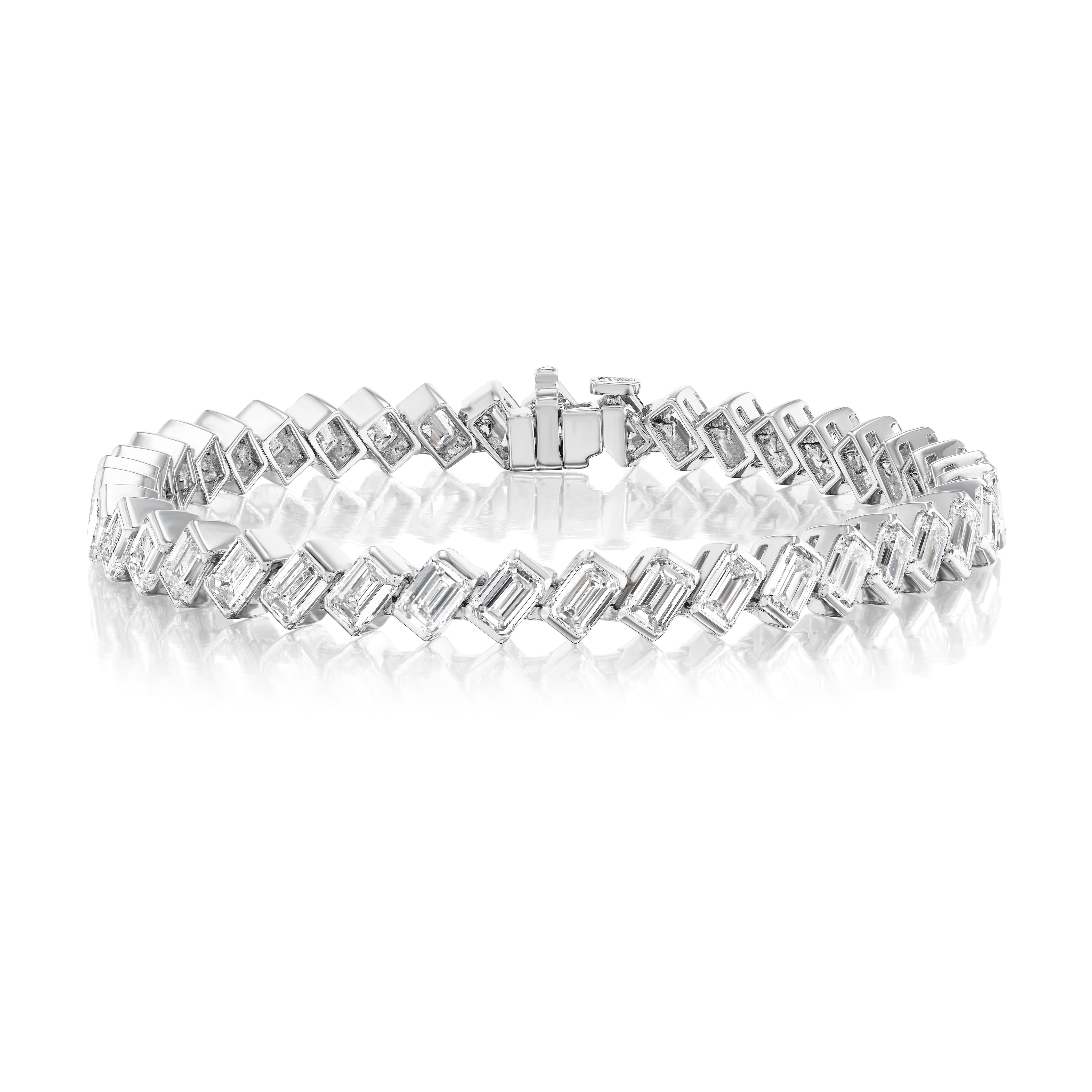 The Diagonal Half Bezel Set Emerald Cut Diamond Tennis Bracelet in Platinum, with emerald-cut diamonds in a diagonal pattern and a secure clasp, is showcased on a white reflective surface.