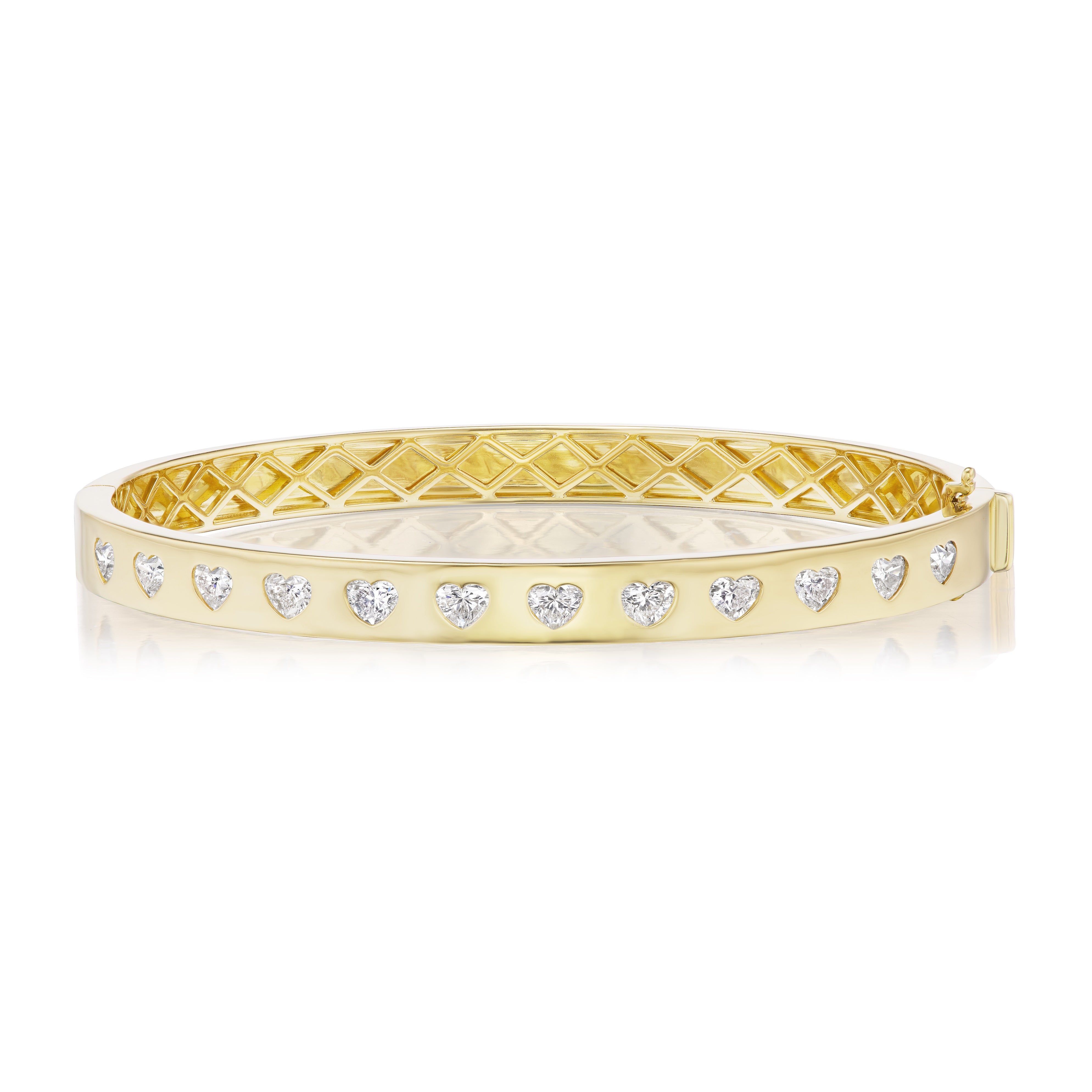 The Burnish Set Heart Shape Diamond Bangle in Yellow Gold showcases SI+ clarity heart-shaped diamonds on the front and a geometric inner pattern, crafted from 18K yellow gold and displayed against a white background.