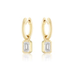 Huggies with Bezel Set Emerald Cut Diamond Charms in Yellow Gold from Serpentine Jewels, shown on a white background. Customize your pair for a unique jewelry look.