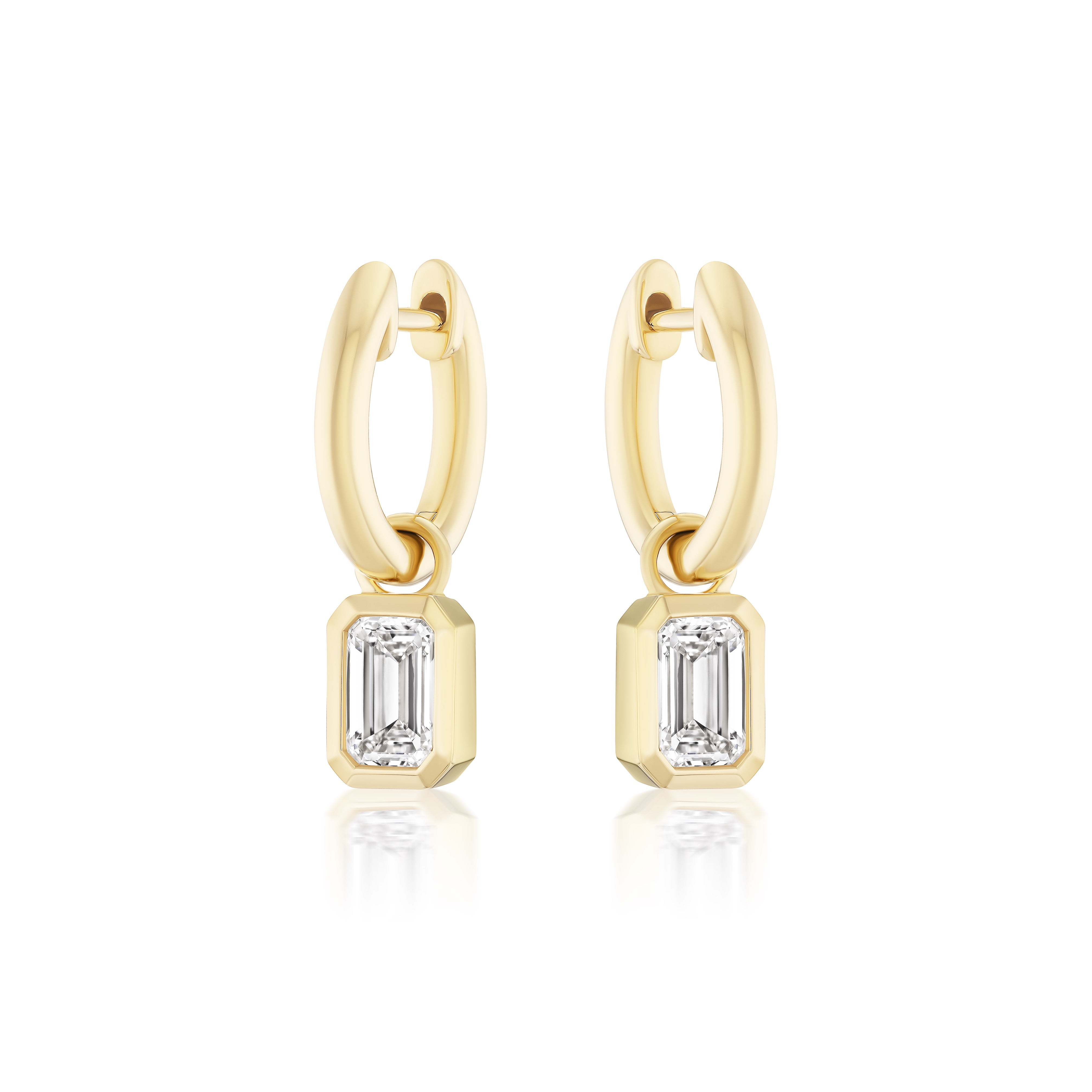 Huggies with Bezel Set Emerald Cut Diamond Charms in Yellow Gold from Serpentine Jewels, shown on a white background. Customize your pair for a unique jewelry look.
