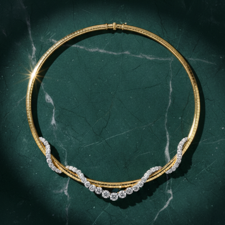 The Coil Graduated Round Diamond and Omega Chain Necklace in Yellow Gold and Platinum is displayed on a dark green marble surface under soft lighting, showcasing its curved, diamond-encrusted design.