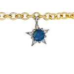 The America250 Ruby, Pearl, Sapphire, and Diamond Charm Bracelet in yellow gold features a star-shaped charm with a central blue sapphire and surrounding diamonds.