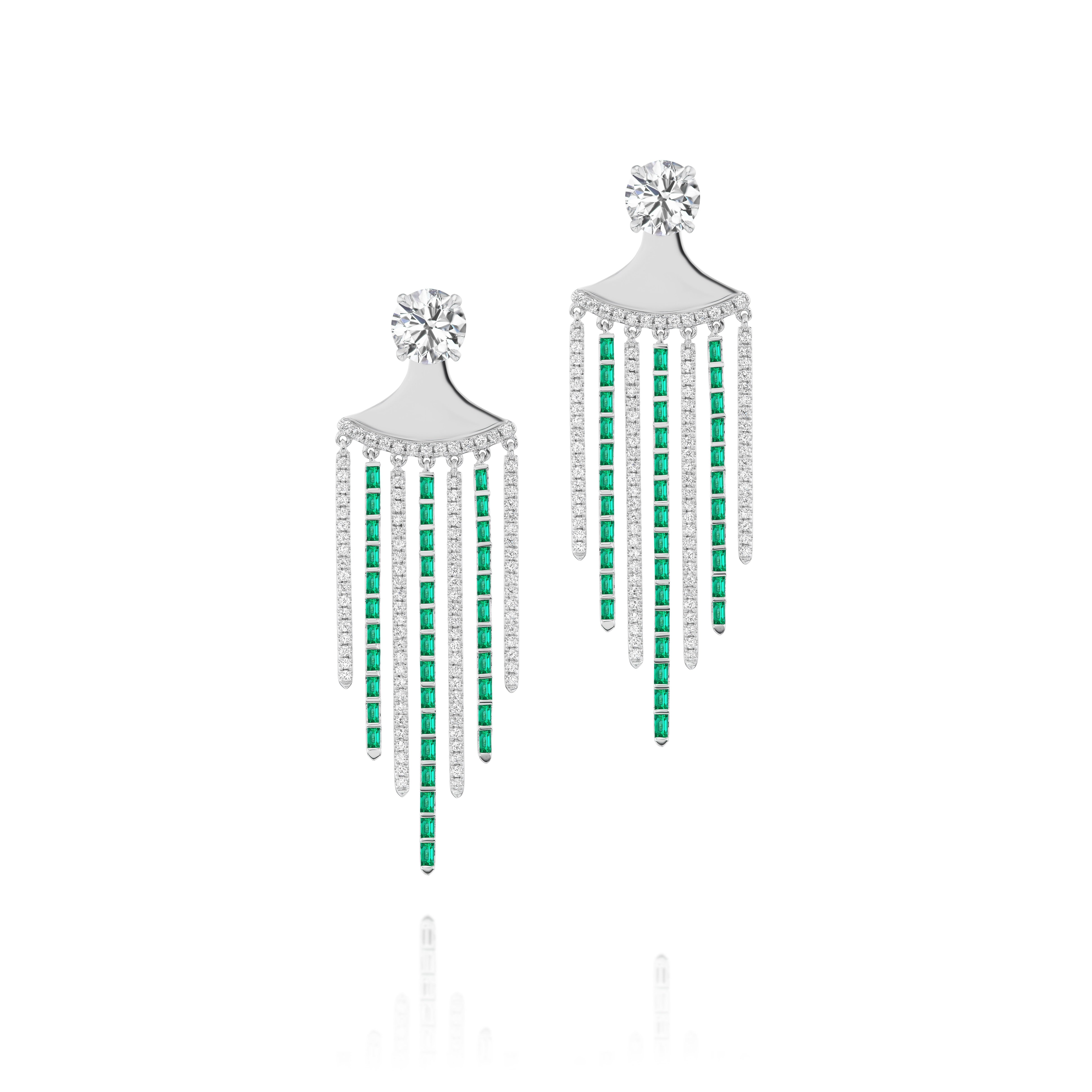 The Raining Diamond and Emerald Ear Jackets in white gold feature a large round diamond at the top and five dangling strands with baguette emeralds and clear stones, creating a stunning fringe effect.