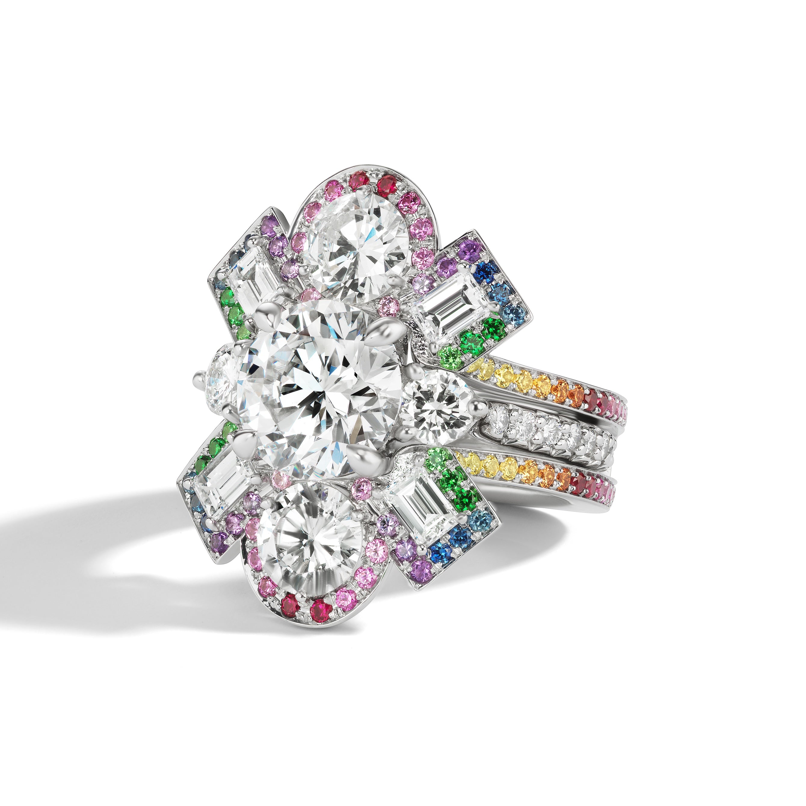 The Bespoke Cross Motif Ring Jacket in white gold features round and emerald cut diamonds, plus a rainbow sapphire pavé halo and band—ideal for pairing with your diamond and sapphire ring.