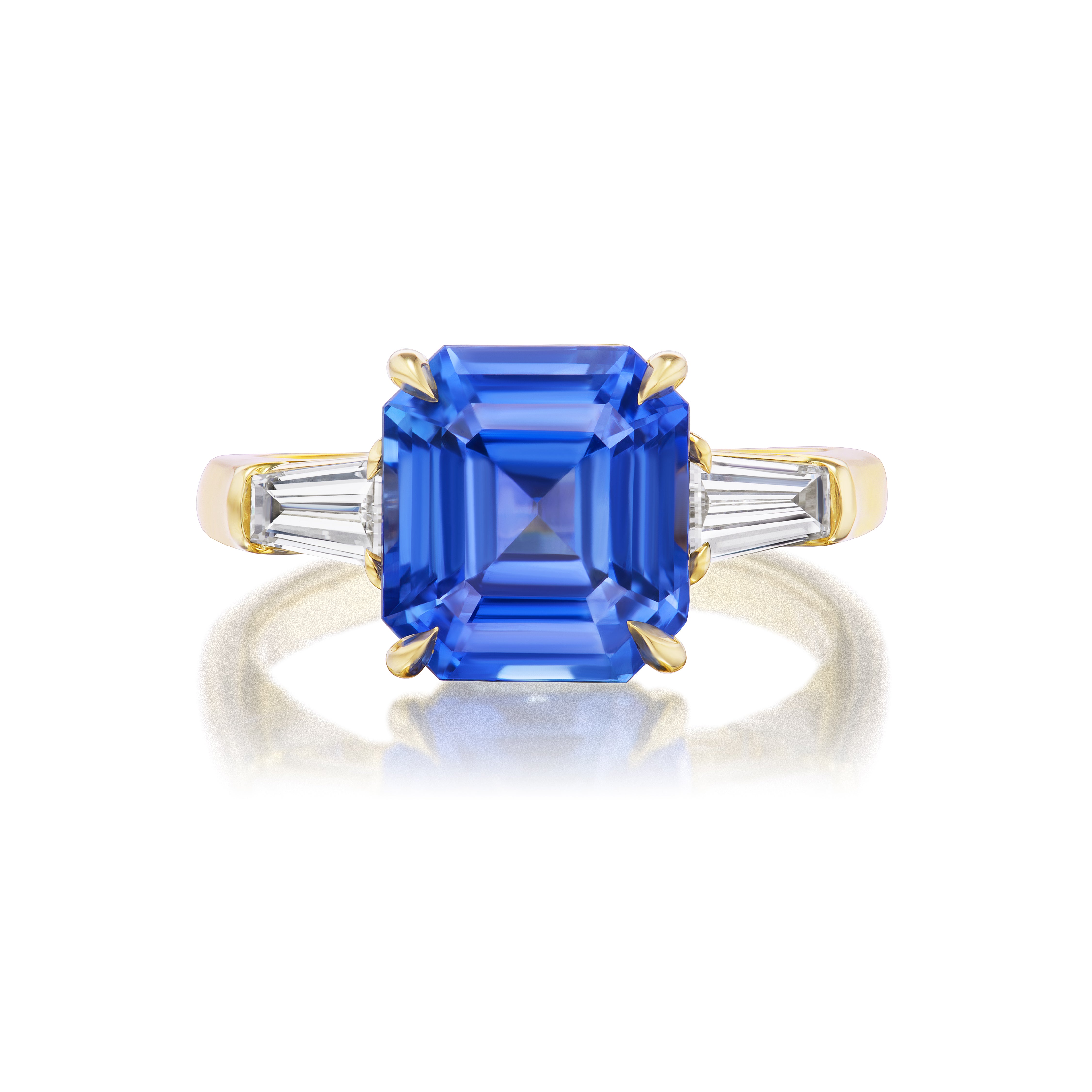 The Asscher Cut Sapphire Engagement Ring features a central Asscher Cut Sapphire in 18K yellow gold, accented by tapered baguette diamond side stones.