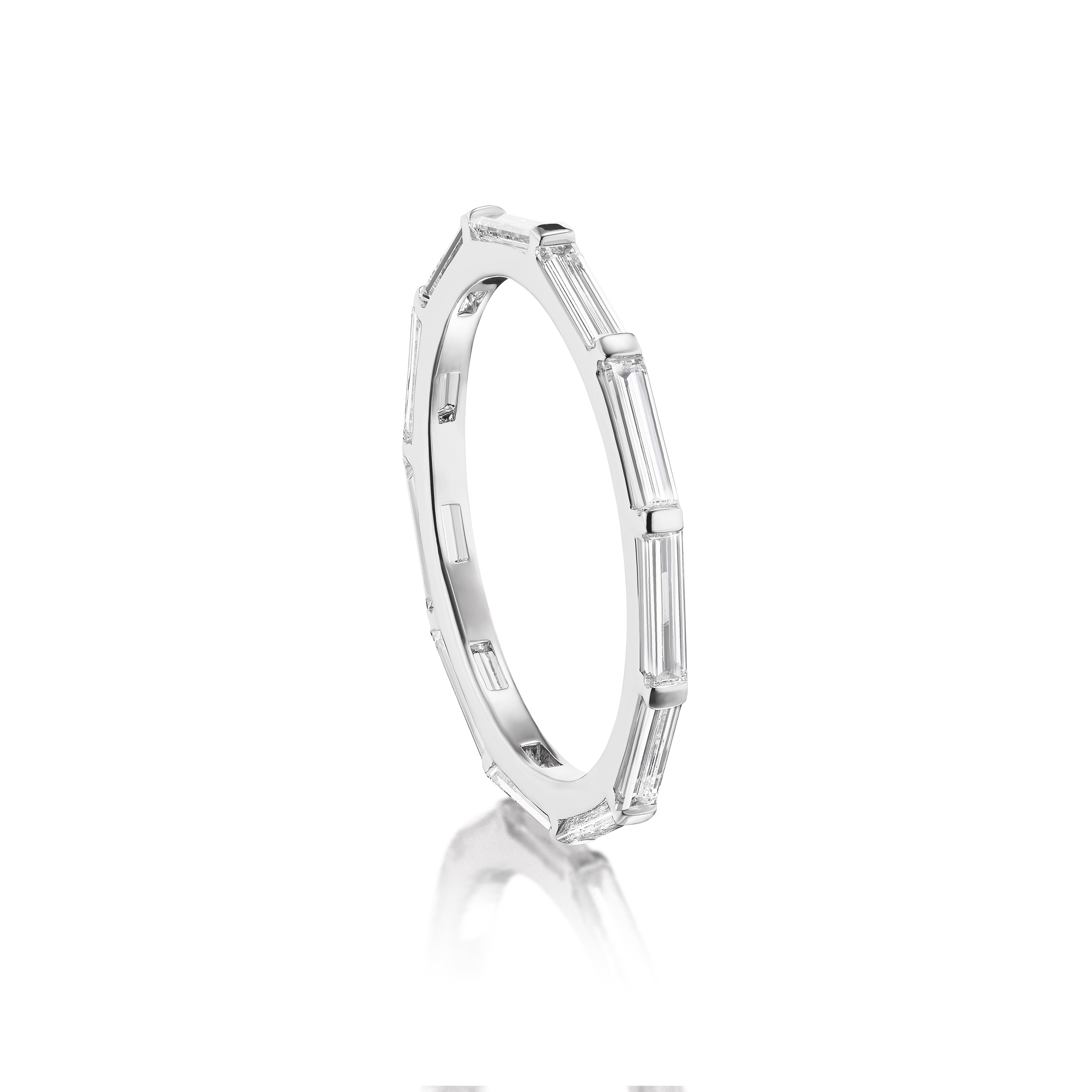 The East-West Thin Baguette Cut Diamond Eternity Band showcases sleek 18K white gold with evenly spaced baguette diamonds around the band, displayed on a white background with a soft reflection below.