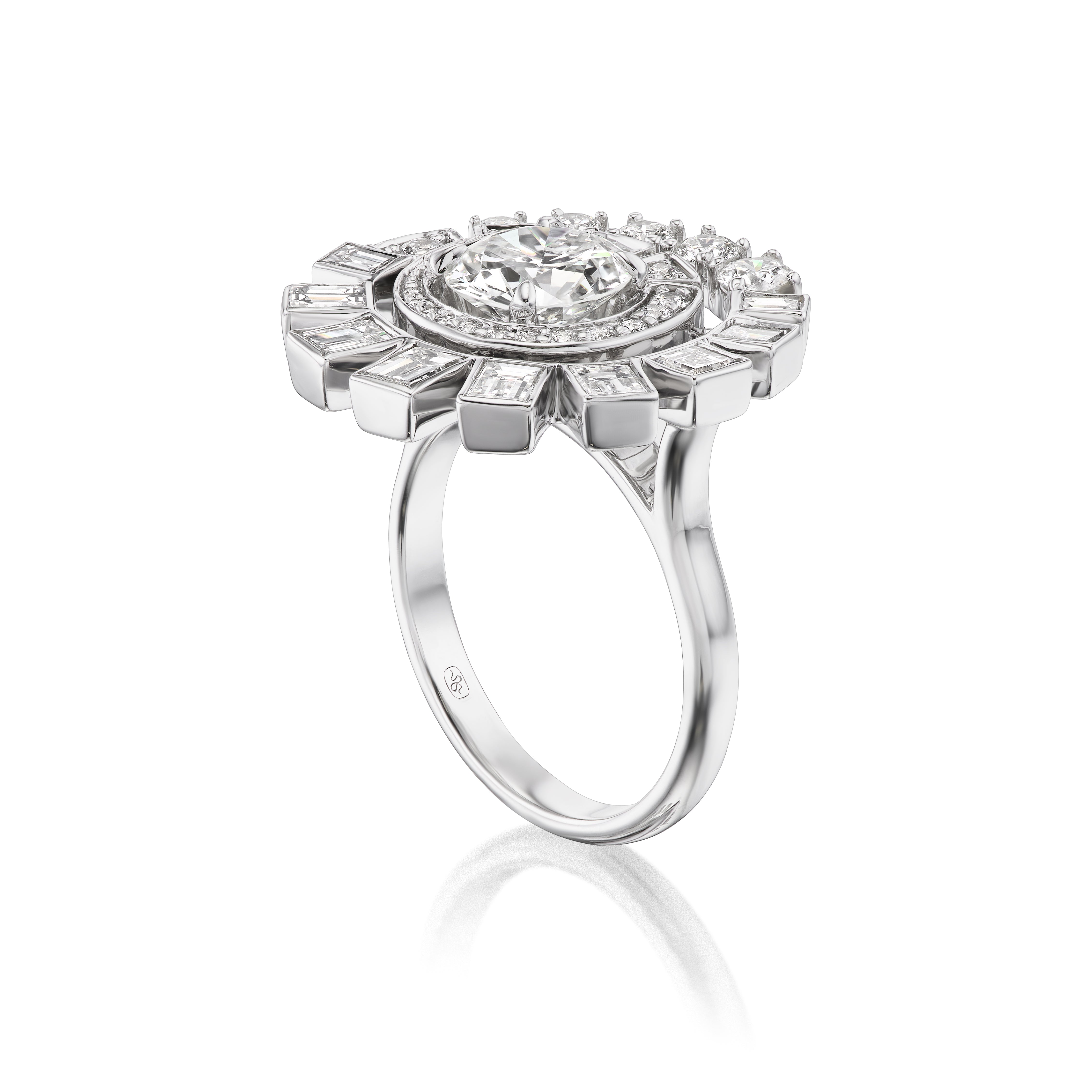 The Spiral Ring in White Gold features a round brilliant central diamond with a sunburst halo of smaller round and baguette diamonds, shown against a white background.
