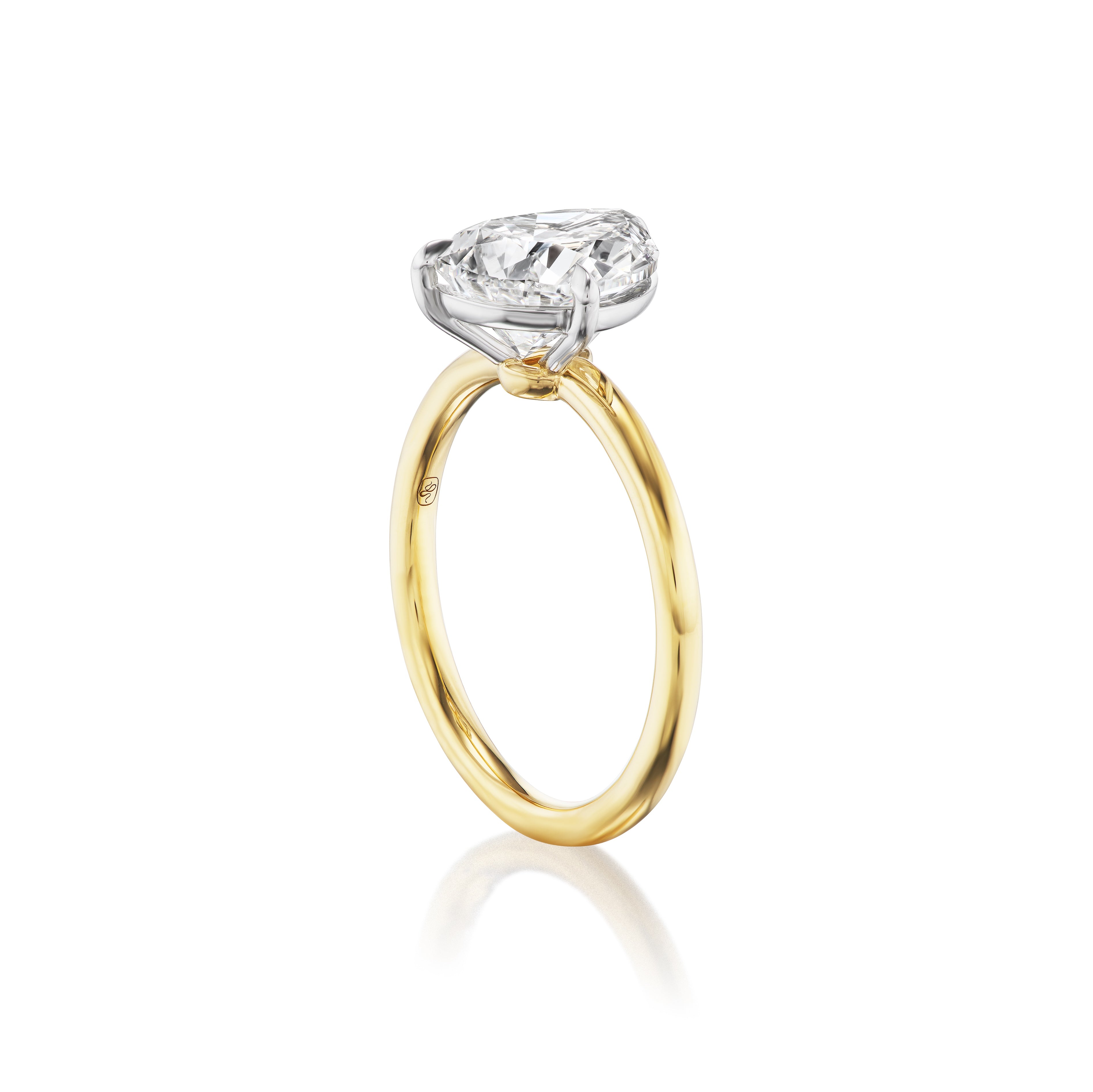 The Diagonally Set Pear Shape Diamond Engagement Ring showcases a striking pear-shaped diamond set at an angle on a slim 18K yellow gold band, with white metal prongs, displayed against a white background.