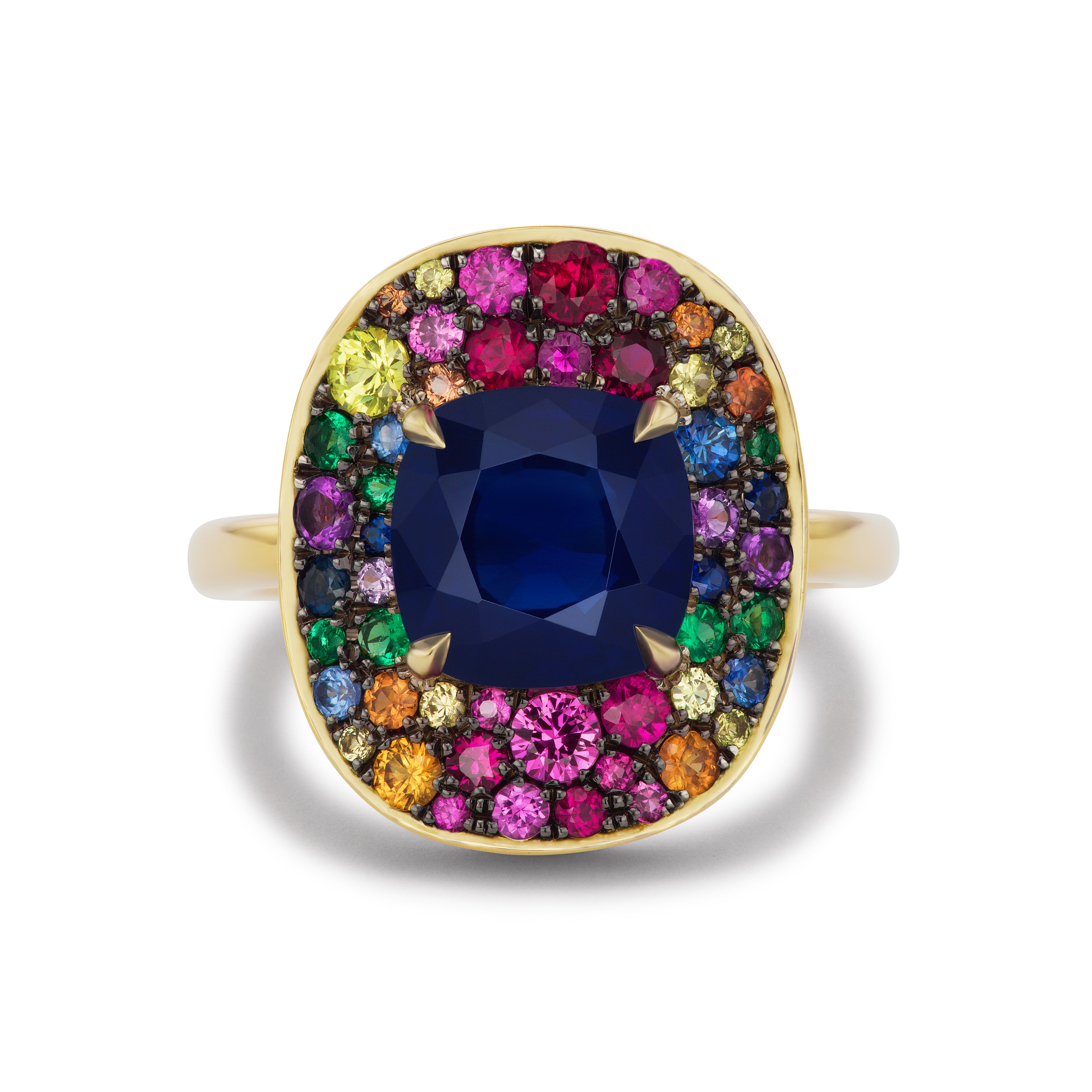 The Cobblestone Cocktail Ring in Yellow Gold features a cushion cut blue sapphire center, framed by multicolor round sapphires in red, yellow, green, purple, and orange, set in an 18K yellow gold square halo design.