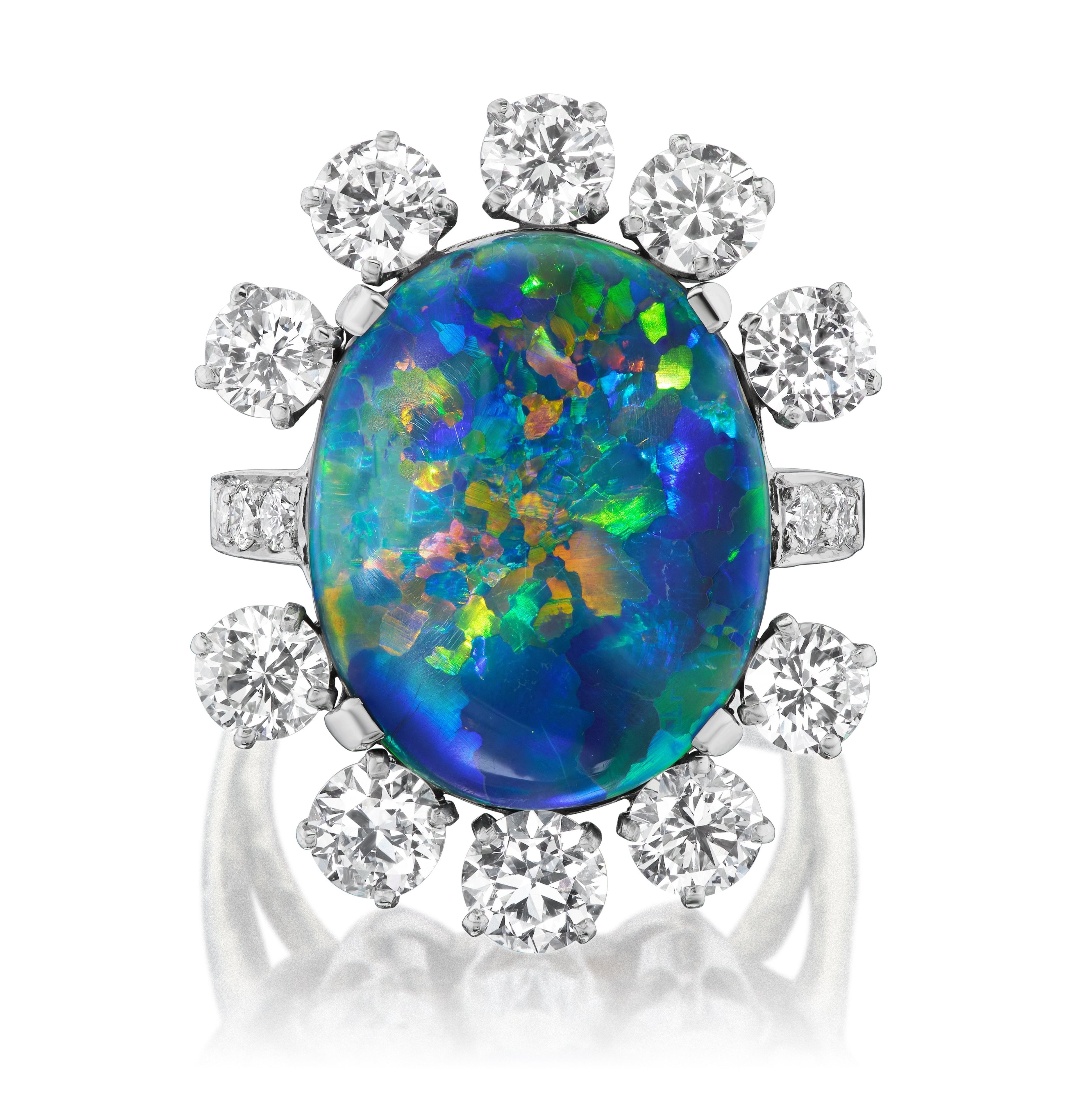 The Sunburst Oval Opal Ring features vibrant blue, green, and orange hues, accented by a halo of round brilliant diamonds and pavé, all set in luxurious 18K white gold.