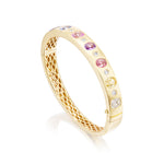 The Burnish Set Multicolor, Mixed Shape, Diamond and Sapphire Bangle in Yellow Gold features a lattice inner band and is adorned with cushion cut sapphires, multicolored gemstones, and diamonds on the top outer surface.