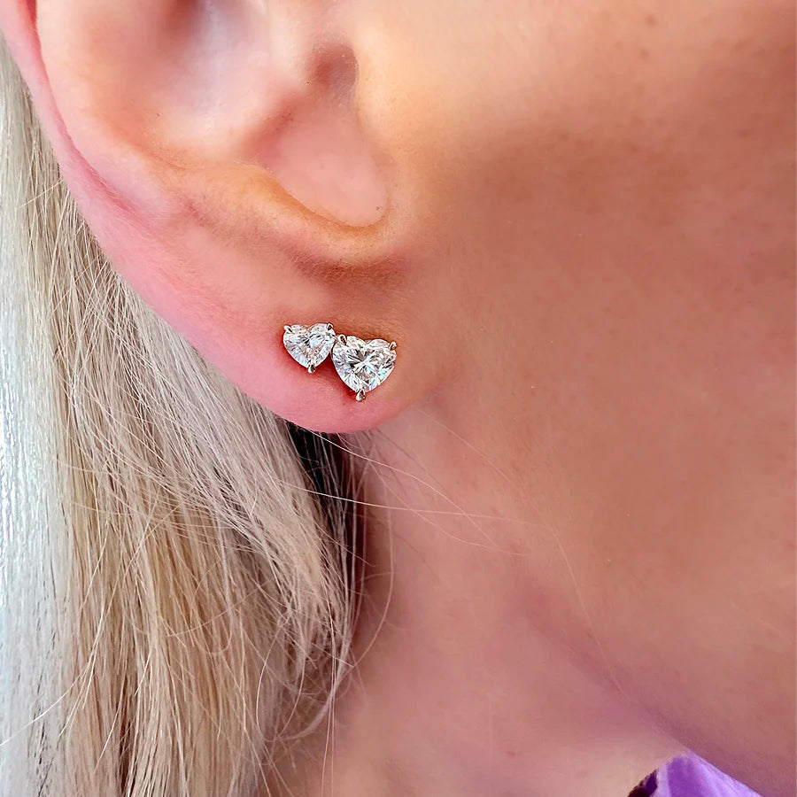 Close-up of a person with light skin and blonde hair wearing Duo Studs in Rose Gold with Heart Diamonds—two small, heart-shaped diamond studs, one above the other—adding delicate sparkle. Made-to-order earrings.