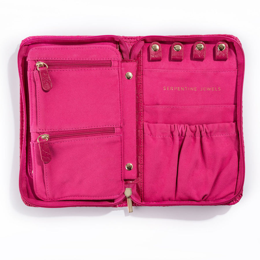 The Serpentine Travel Case is a bright pink vegan leather jewelry organizer with two zippered left pockets, four snap loops and two gathered right pouches, plus gold "Serpentine Jewels" text.