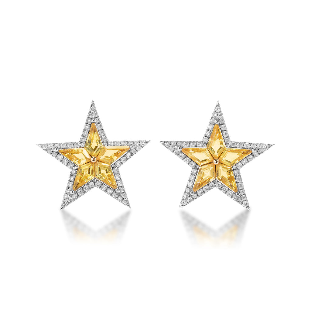 Celestial Star Studs in white gold feature yellow kite sapphires at the center, bordered by diamond pavé, with a star-shaped design inspired by the cosmos, shown against a white background.