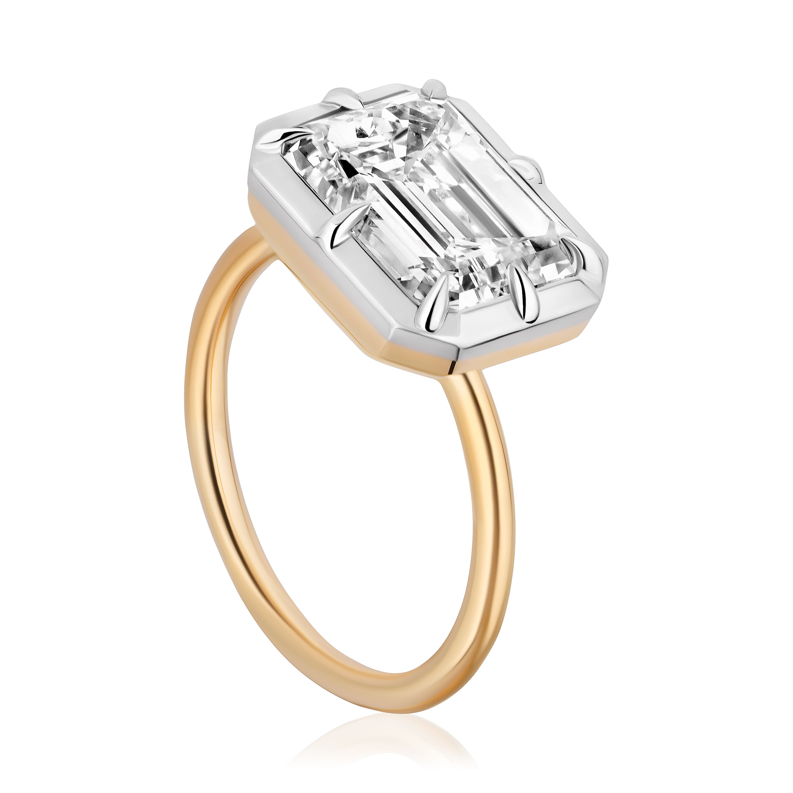 The East-West Collet Setting Emerald Cut Diamond Engagement Ring features a large emerald-cut diamond in a geometric white metal prong setting, showcased on a white background.