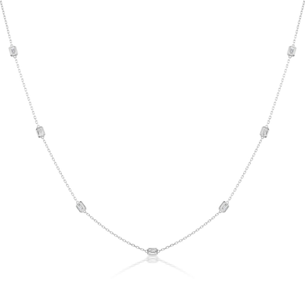 The Serpentine Station Necklace features emerald cut diamonds set in 18K white gold, with rectangular gemstones spaced along a fine chain, shown on a plain white background.