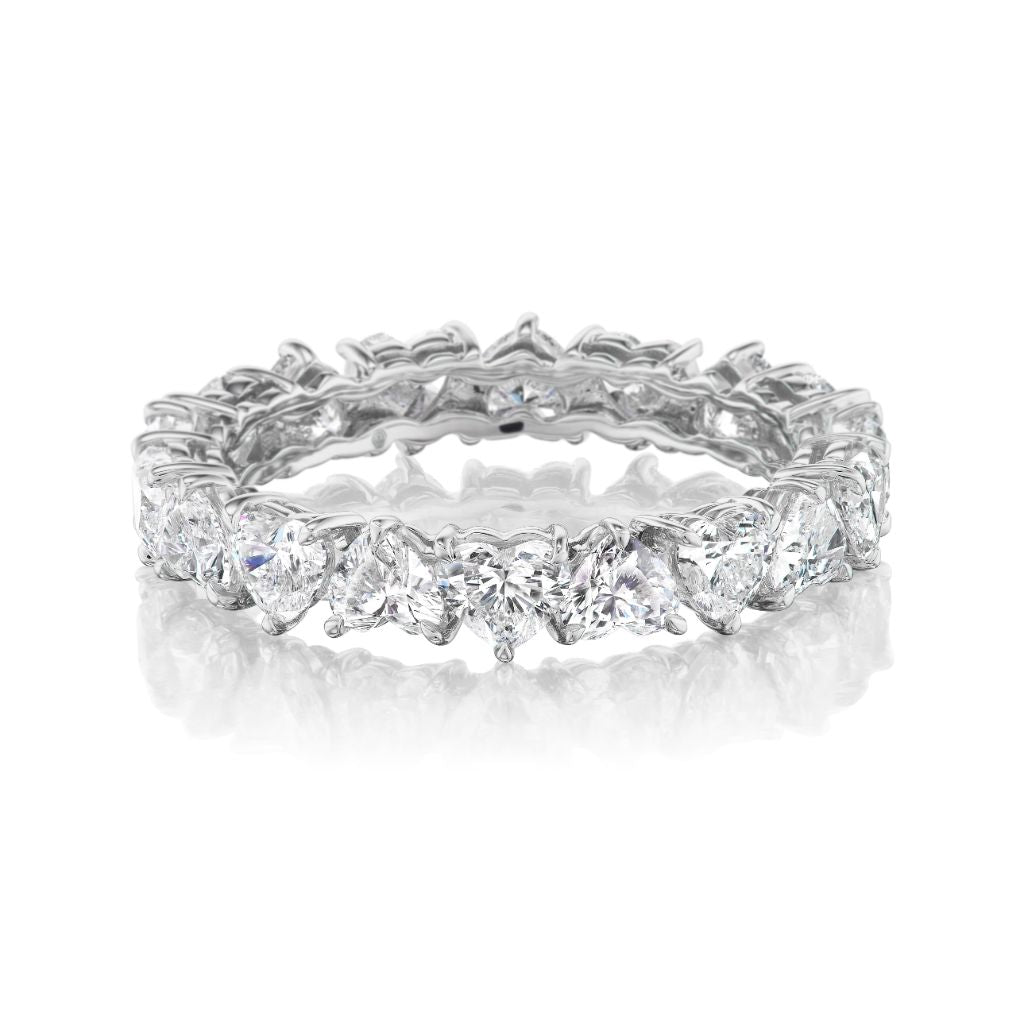 The Up and Down Heart Diamond Eternity Band in platinum showcases a continuous row of white and heart-shaped diamonds encircling the ring, beautifully displayed on a white reflective surface.