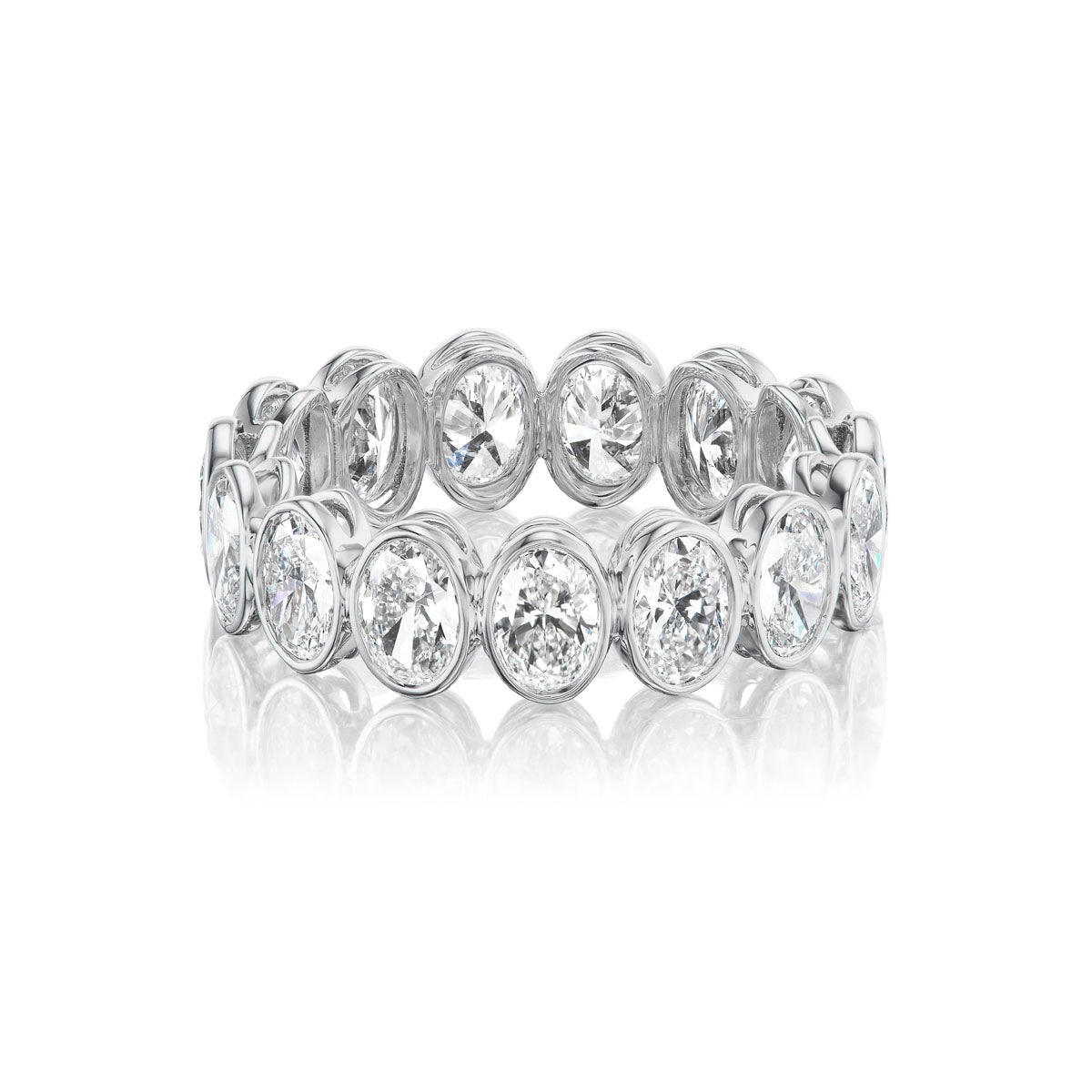 The Oval Bezel Set Diamond Eternity Band in White Gold features oval diamonds in individual bezel settings around the band, shown on a white background with a subtle reflection at the base.