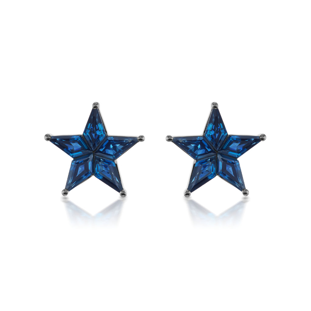 The Celestial Star Studs in Black Rhodium feature kite-shaped deep blue sapphires set in an 18K black rhodium base, showcased on a white background—a celestial accessory to elevate any look with elegant charm.