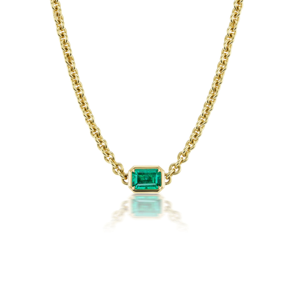 The Chunky Chain Necklace in Yellow Gold with Emerald Cut Emerald showcases a bold chain and a bezel-set emerald pendant, crafted from 18K yellow gold, and is photographed on a white background.