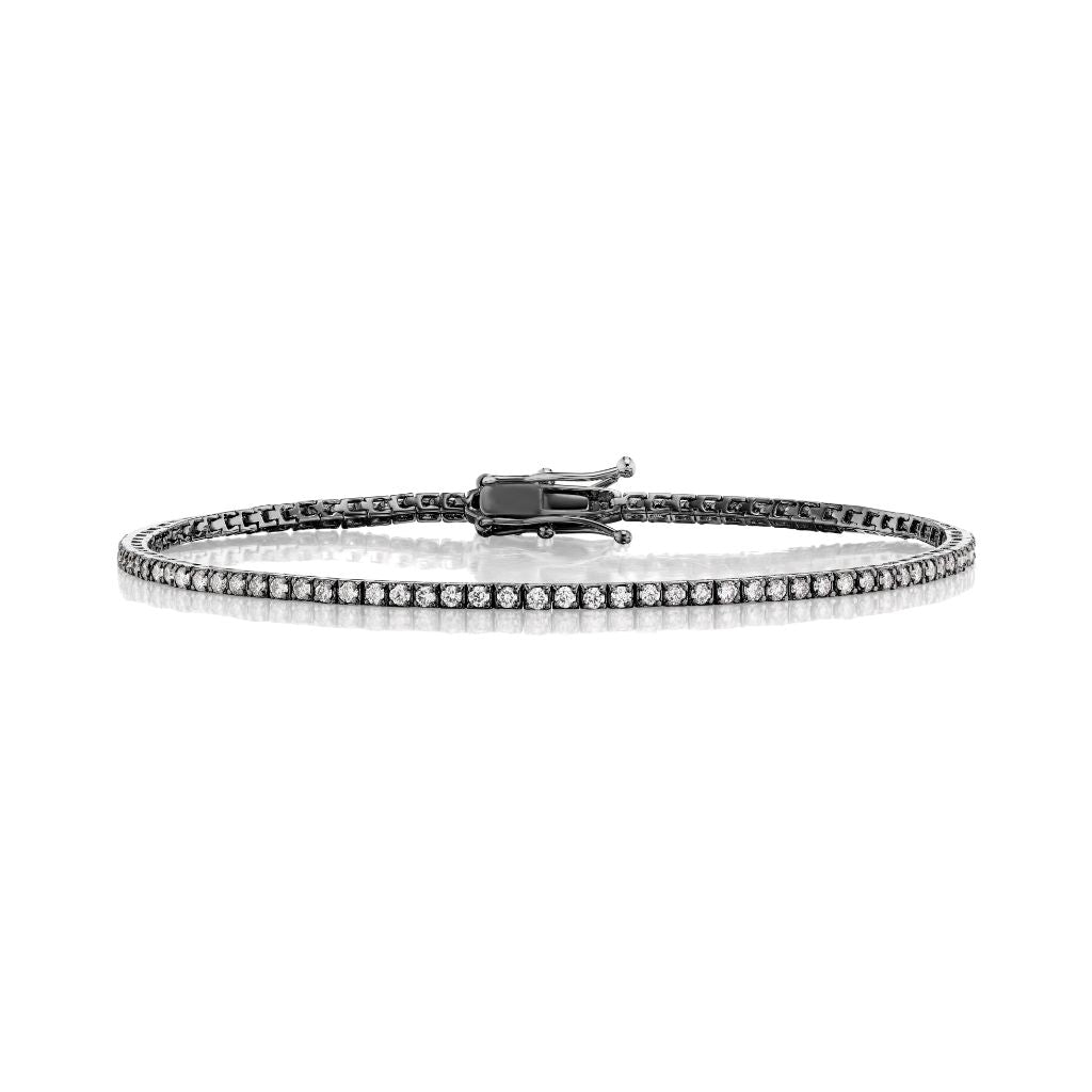 The Skinny Round Brilliant Diamond Tennis Bracelet is a slim black bracelet showcasing a single row of round brilliant diamonds set in dark metal with a secure center clasp.
