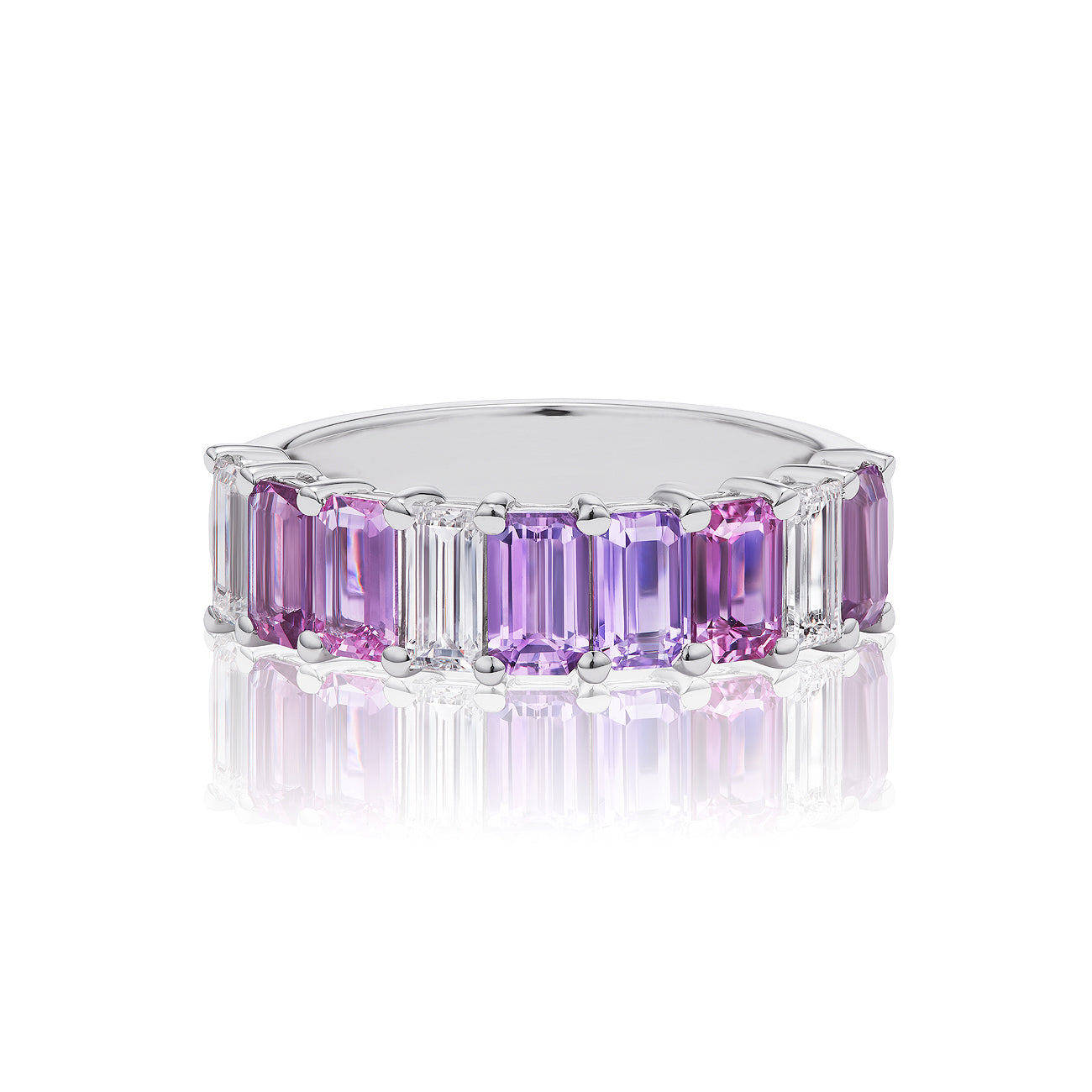An Emerald Cut Half Eternity Band in white gold with diamonds and multicolored sapphires is displayed on a reflective white background.