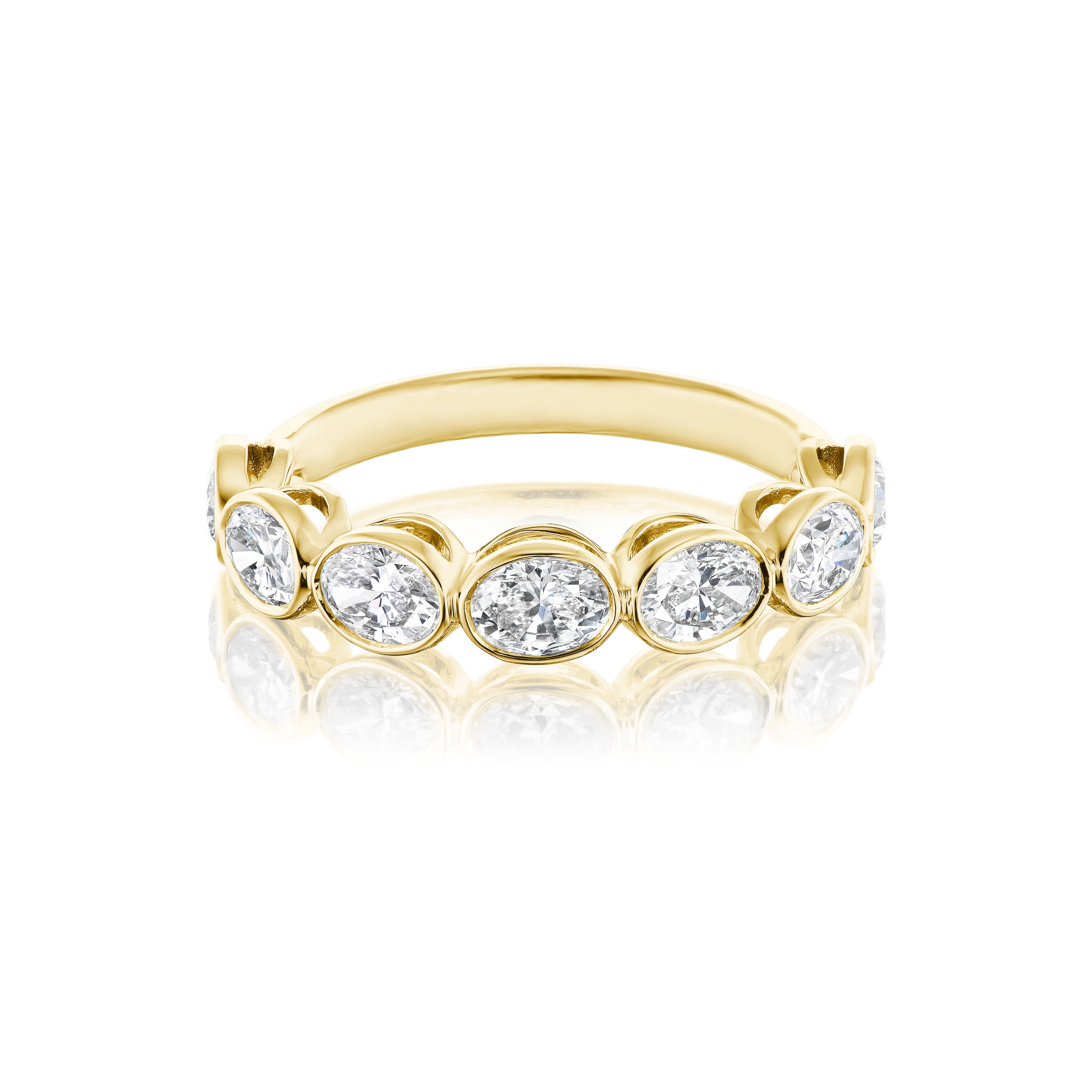 The Chasing Ovals Bezel Set Diamond Half Eternity Band features seven oval-cut white diamonds set horizontally in bezels, displayed on a reflective white background—an elegant bridal ring choice.